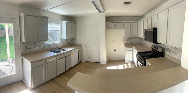 15316 Lady Elizabeth Ln, Pflugerville, TX 78660 - kitchen featuring stainless steel electric stove, white dishwasher, a peninsula, decorative backsplash, and light wood finished floors