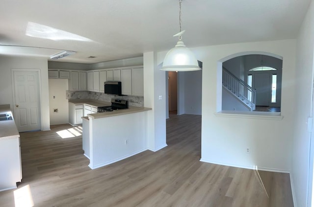 15316 Lady Elizabeth Ln, Pflugerville, TX 78660 - kitchen featuring stainless steel electric range, light wood-style flooring, backsplash, and arched walkways