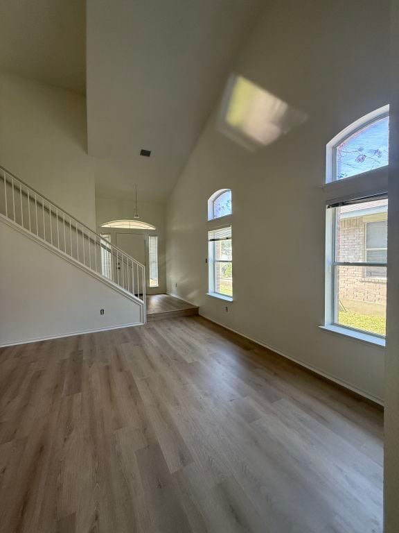 15316 Lady Elizabeth Ln, Pflugerville, TX 78660 - unfurnished living room featuring high vaulted ceiling, wood finished floors, and stairs