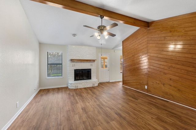 3419 Bluebonnet Trl, Georgetown, TX 78628 - unfurnished living room with a ceiling fan, wood finished floors, a brick fireplace, and wood walls