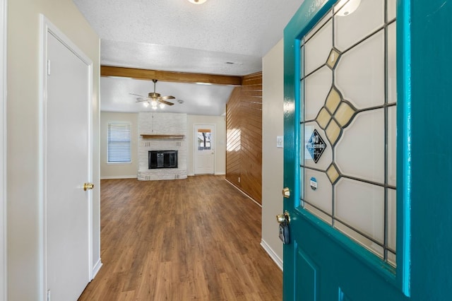 3419 Bluebonnet Trl, Georgetown, TX 78628 - foyer entrance with ceiling fan, beamed ceiling, wood finished floors, a textured ceiling, and a fireplace