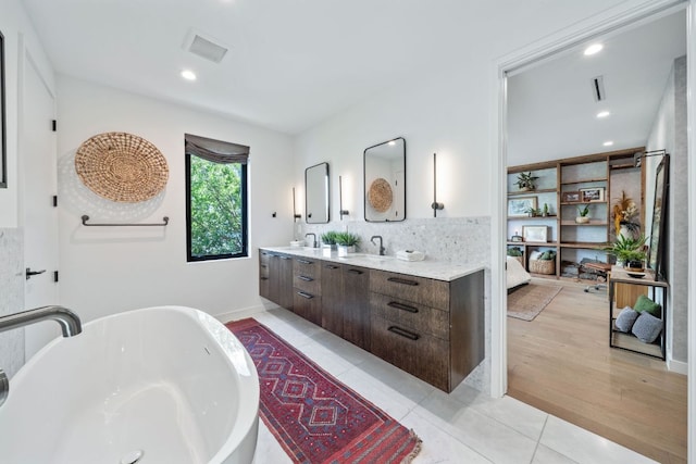 2309 E 5th St, Austin, TX 78702 - ensuite bathroom featuring a freestanding tub, double vanity, decorative backsplash, recessed lighting, and tile patterned flooring