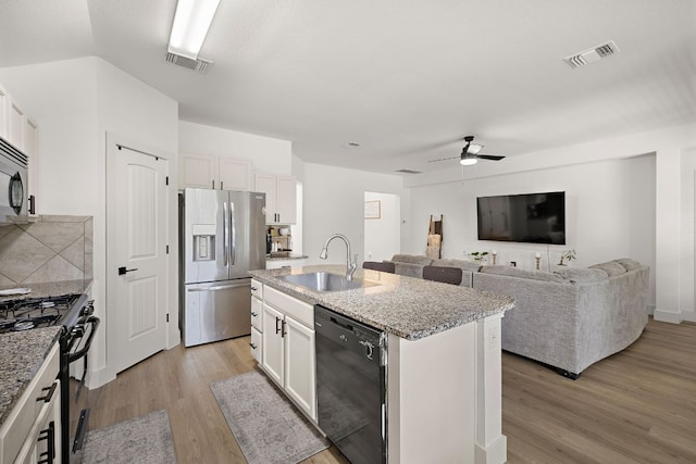 413 Luna Vista Dr, Hutto, TX 78634 - kitchen featuring black appliances, a ceiling fan, light wood finished floors, a kitchen island with sink, and tasteful backsplash