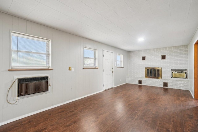 1620 Cavett St, Gonzales, TX 78629 - unfurnished living room featuring a brick fireplace, wood finished floors, and a wall unit AC