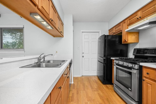 4800 Lansing Dr, Austin, TX 78745 - kitchen with stainless steel appliances, under cabinet range hood, light wood finished floors, light countertops, and brown cabinetry