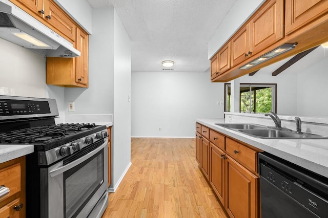 4800 Lansing Dr, Austin, TX 78745 - kitchen with stainless steel range with gas stovetop, under cabinet range hood, black dishwasher, light wood-style flooring, and light countertops