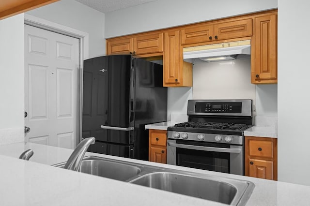 4800 Lansing Dr, Austin, TX 78745 - kitchen with freestanding refrigerator, under cabinet range hood, stainless steel range with gas cooktop, and light countertops
