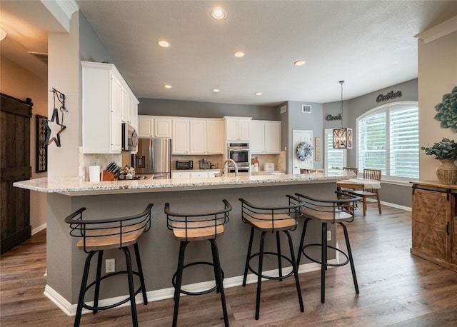 401 Kimra Cv, Georgetown, TX 78628 - kitchen featuring appliances with stainless steel finishes, light stone countertops, dark wood-style flooring, white cabinetry, and recessed lighting