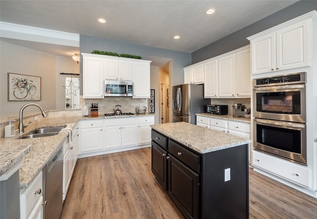 401 Kimra Cv, Georgetown, TX 78628 - kitchen featuring appliances with stainless steel finishes, white cabinets, light wood-style floors, and recessed lighting