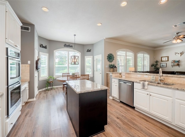 401 Kimra Cv, Georgetown, TX 78628 - kitchen with appliances with stainless steel finishes, recessed lighting, light wood-type flooring, white cabinetry, and a kitchen island