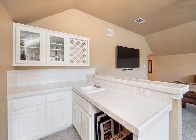 401 Kimra Cv, Georgetown, TX 78628 - kitchen featuring lofted ceiling, a peninsula, glass insert cabinets, and tile counters