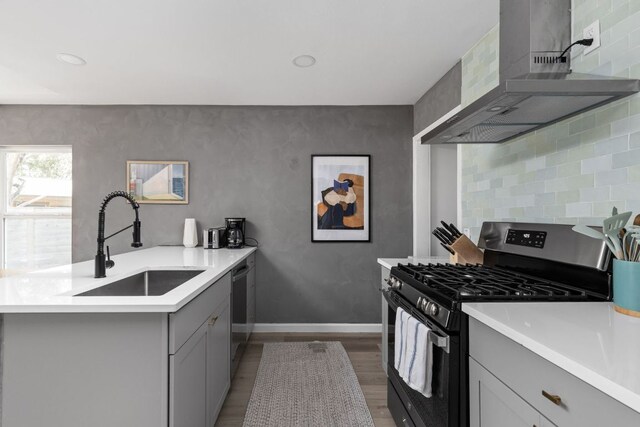 4911 Brighton Rd, Austin, TX 78745 - kitchen with appliances with stainless steel finishes, wall chimney exhaust hood, gray cabinetry, wood finished floors, and light countertops