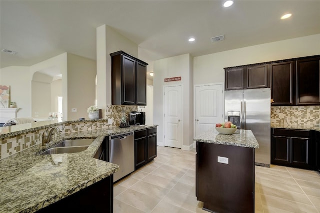 578 Ledge Stone Dr, Austin, TX 78737 - kitchen featuring stainless steel appliances, light stone counters, tasteful backsplash, light tile patterned flooring, and dark brown cabinets