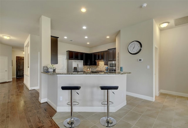 578 Ledge Stone Dr, Austin, TX 78737 - kitchen featuring stainless steel appliances, stone countertops, a breakfast bar area, tasteful backsplash, and recessed lighting