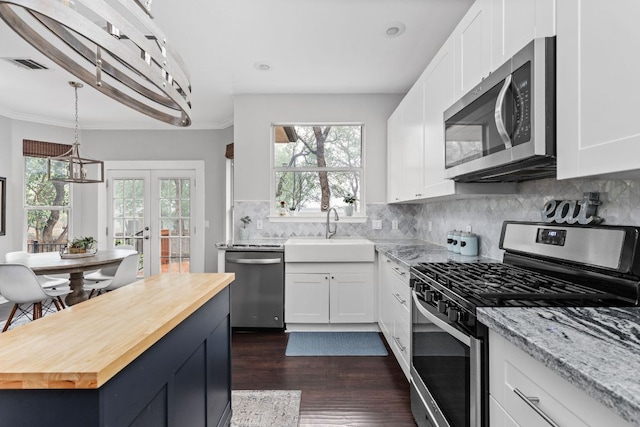 4112 Seldalia Trl, Austin, TX 78732 - kitchen with appliances with stainless steel finishes, wood counters, dark wood-type flooring, white cabinetry, and crown molding
