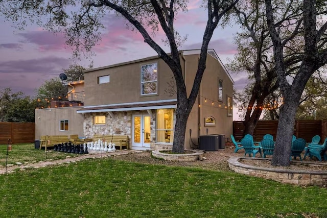 17708 Cherry Ln, Lago Vista, TX 78645 - back of property at dusk with a patio, stucco siding, stone siding, and a balcony