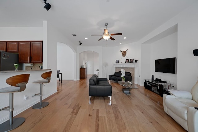 15800 Tetons Ct, Bee Cave, TX 78738 - living room featuring arched walkways, a ceiling fan, light wood-style floors, recessed lighting, and a tile fireplace