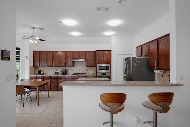 15800 Tetons Ct, Bee Cave, TX 78738 - kitchen featuring appliances with stainless steel finishes, backsplash, a breakfast bar area, and a peninsula