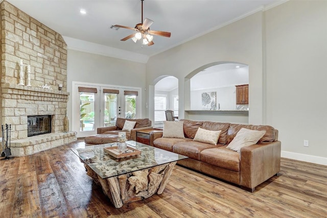 30613 Chi Chi Dr, Georgetown, TX 78628 - living area with a ceiling fan, arched walkways, light wood-style floors, crown molding, and a stone fireplace