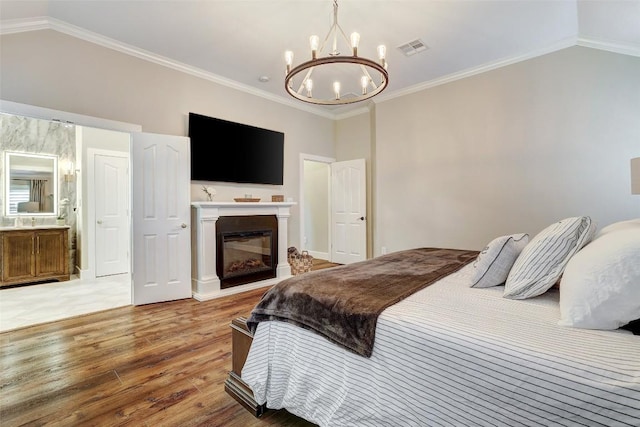 30613 Chi Chi Dr, Georgetown, TX 78628 - bedroom featuring light wood-style floors, a chandelier, a glass covered fireplace, lofted ceiling, and crown molding