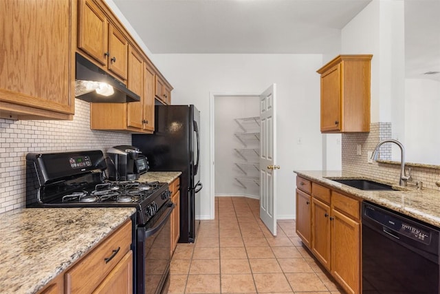 3710 Castle Rock Dr, Round Rock, TX 78681 - kitchen with black appliances, under cabinet range hood, decorative backsplash, light stone counters, and light tile patterned floors