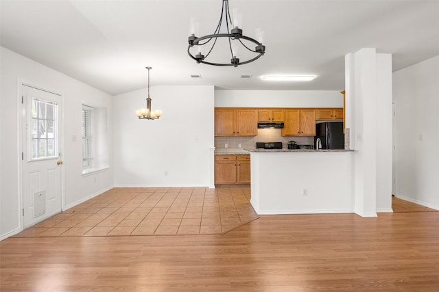 3710 Castle Rock Dr, Round Rock, TX 78681 - kitchen with freestanding refrigerator, a chandelier, under cabinet range hood, brown cabinetry, and stove