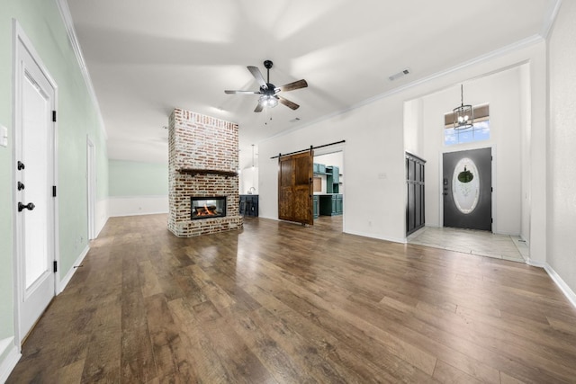1409 Castle Ridge Dr, Harker Heights, TX 76548 - unfurnished living room with a barn door, ceiling fan, hardwood / wood-style flooring, crown molding, and a brick fireplace