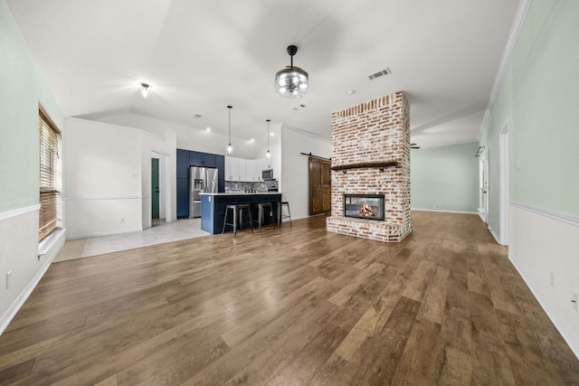 1409 Castle Ridge Dr, Harker Heights, TX 76548 - unfurnished living room with light wood finished floors, a barn door, a fireplace, and lofted ceiling