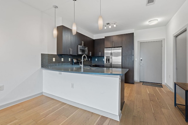 3600 S Lamar Blvd Unit 501, Austin, TX 78704 - kitchen with stainless steel appliances, a peninsula, light wood-style flooring, and tasteful backsplash
