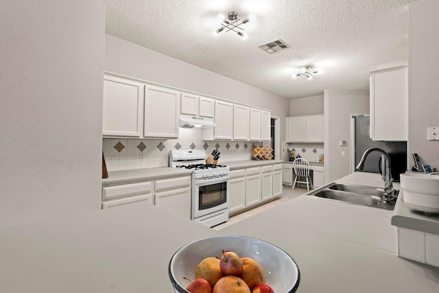 16907 Cranston Dr, Round Rock, TX 78664 - kitchen with white gas stove, under cabinet range hood, decorative backsplash, a textured ceiling, and white cabinetry