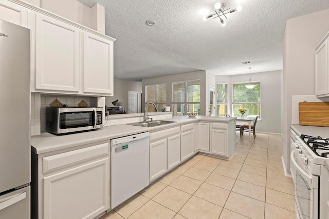 16907 Cranston Dr, Round Rock, TX 78664 - kitchen featuring appliances with stainless steel finishes, a textured ceiling, a peninsula, light tile patterned floors, and light countertops