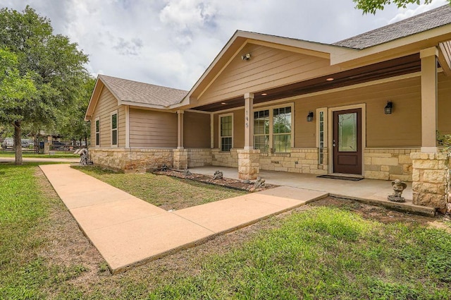 195 Heritage Oaks Dr, Cedar Creek, TX 78612 - view of exterior entry with stone siding, a porch, and a yard