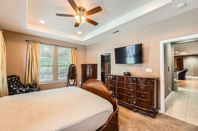195 Heritage Oaks Dr, Cedar Creek, TX 78612 - bedroom with a walk in closet, light carpet, light tile patterned floors, a ceiling fan, and a tray ceiling