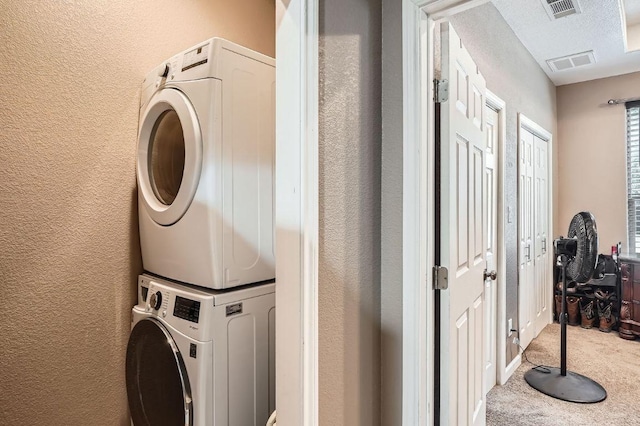 195 Heritage Oaks Dr, Cedar Creek, TX 78612 - laundry area featuring stacked washer / drying machine, a textured wall, and carpet floors