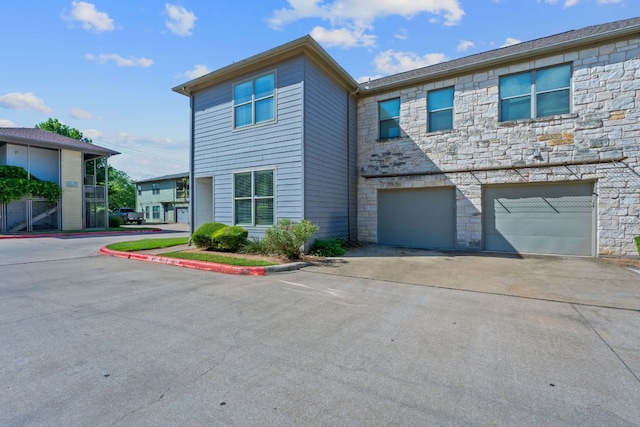 1201 Grove Blvd Unit 2203, Austin, TX 78741 - view of property with stone siding, a garage, and driveway