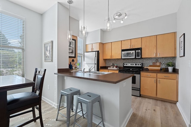 1201 Grove Blvd Unit 2203, Austin, TX 78741 - kitchen featuring stainless steel appliances, dark countertops, light wood finished floors, and a breakfast bar