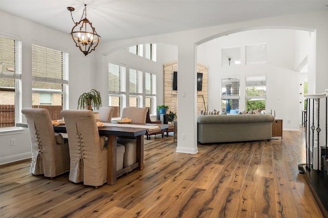 4539 Miraval Loop, Round Rock, TX 78665 - dining space featuring arched walkways, hardwood / wood-style floors, a chandelier, and a towering ceiling