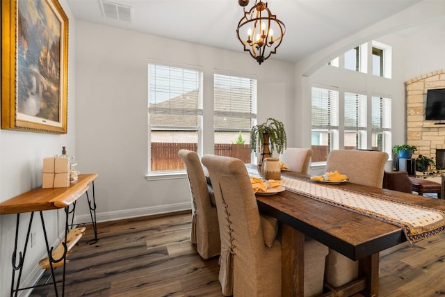 4539 Miraval Loop, Round Rock, TX 78665 - dining space with wood finished floors, a chandelier, a stone fireplace, and arched walkways