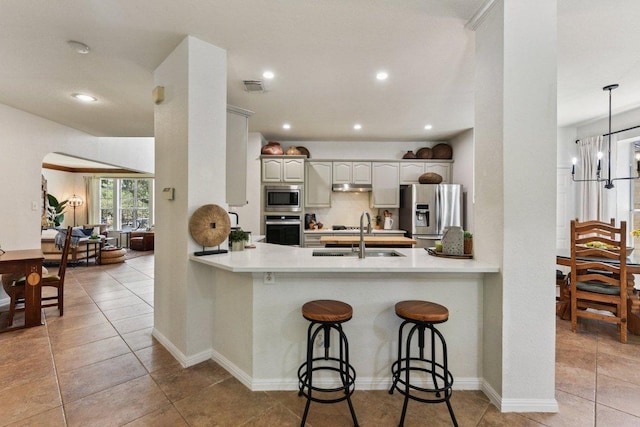 1224 Fall Creek Loop, Cedar Park, TX 78613 - kitchen with stainless steel appliances, a peninsula, a breakfast bar area, arched walkways, and recessed lighting