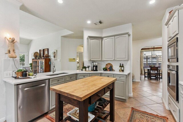 1224 Fall Creek Loop, Cedar Park, TX 78613 - kitchen with stainless steel appliances, arched walkways, recessed lighting, light tile patterned floors, and a peninsula