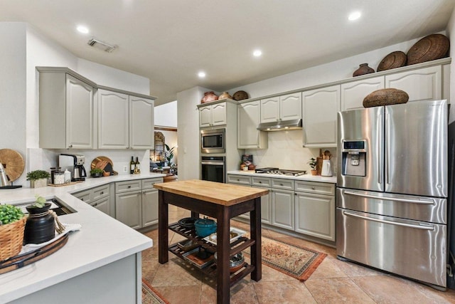 1224 Fall Creek Loop, Cedar Park, TX 78613 - kitchen with stainless steel appliances, under cabinet range hood, light countertops, gray cabinetry, and decorative backsplash