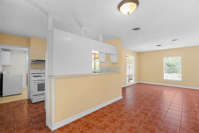7923 Brockman St, Austin, TX 78757 - kitchen featuring white gas range oven, washer / clothes dryer, under cabinet range hood, tile patterned floors, and a textured ceiling