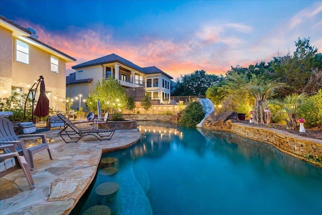 pool at dusk with a patio and an outdoor pool