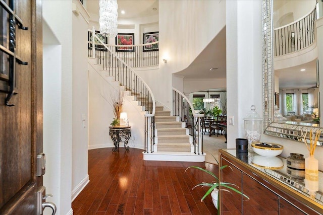 entrance foyer featuring a towering ceiling, stairway, healthy amount of natural light, a chandelier, and wood finished floors