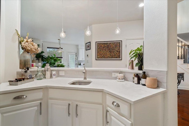 kitchen with light stone countertops, decorative light fixtures, white cabinets, and wood finished floors