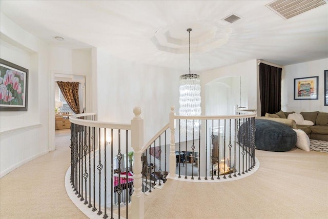 hallway with an upstairs landing, carpet flooring, and a chandelier
