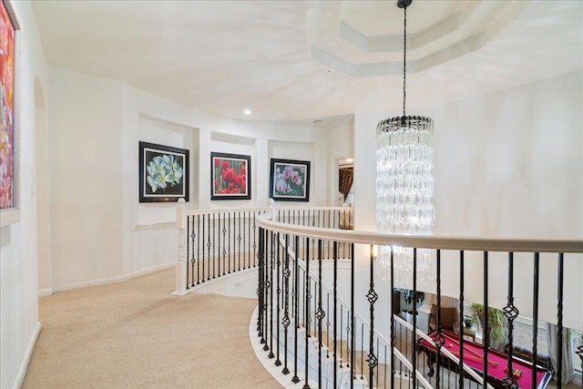 hall with an upstairs landing, a chandelier, and carpet