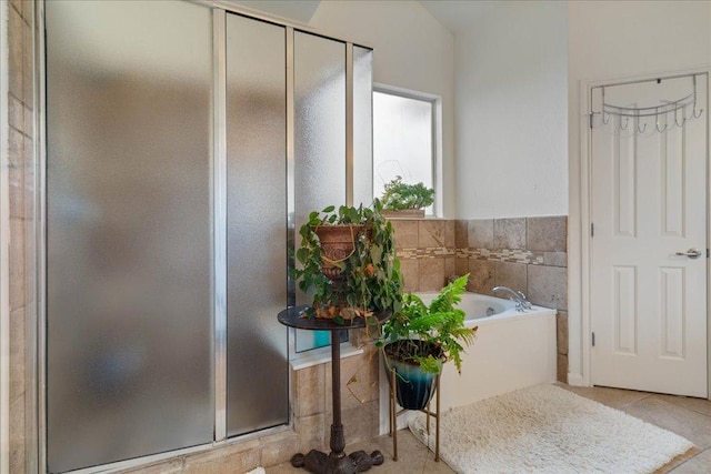 full bathroom featuring a stall shower, a bath, and tile patterned floors