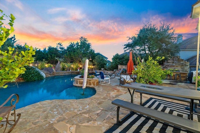pool at dusk featuring a patio area and an outdoor pool