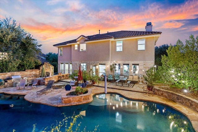 rear view of house with a chimney, a patio, a tiled roof, an outdoor pool, and stucco siding